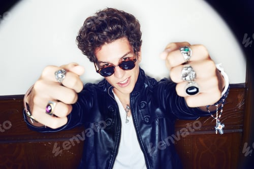 Preview: Awesome. Portrait of a stylish young man with both ring-clad fists pointed at the camera.