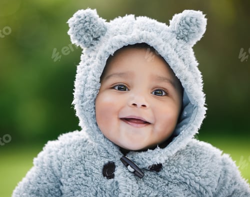 Preview: Portrait of an adorable baby boy wearing a furry jacket with bear ears outdoors