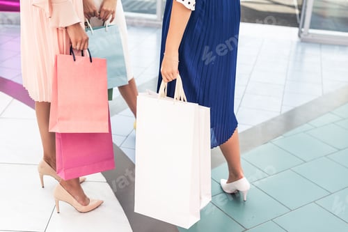 Preview: cropped shot of stylish girls holding paper bags in shopping mall