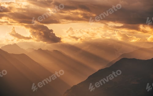Preview: Amazing dramatic cloudscape in sunset with sun rays over misty mountains landscape