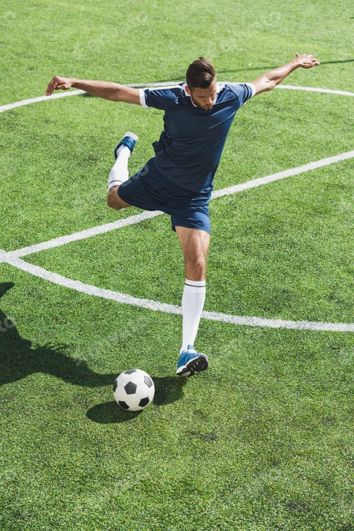 Preview: athletic soccer player kicking ball on soccer pitch