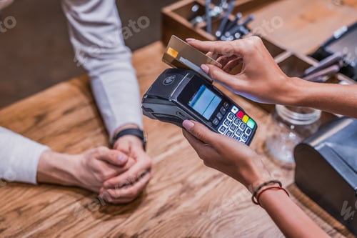 Preview: Cropped shot of female barista making payment by customer's credit card