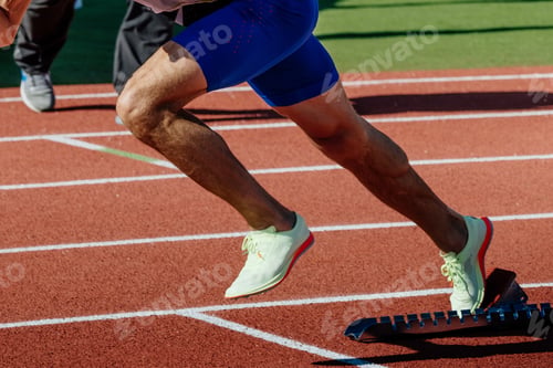 Preview: close-up legs male runner running in starting blocks sprint race