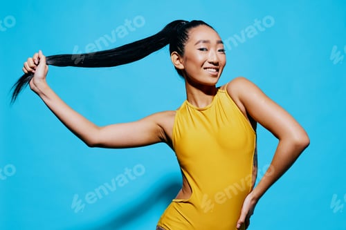 Preview: Smiling Woman in Yellow Leotard Poses with Ponytail