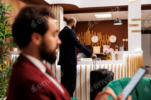 Preview: Businessman with luggage at front desk