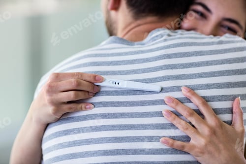 Preview: Happy couple hugging with positive pregnancy test in bathroom