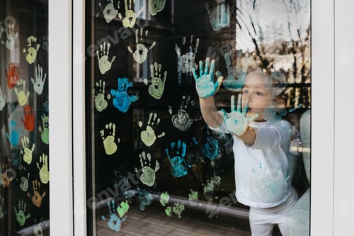 Preview: Girl paints with palms on the window. Quarantine Stay at home