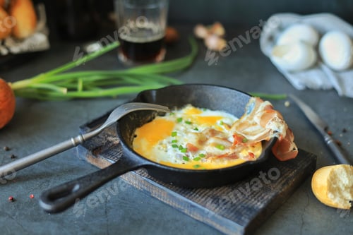 Preview: Scrambled eggs with bacon in a frying pan on the table, beer and other ingredients for a lunch