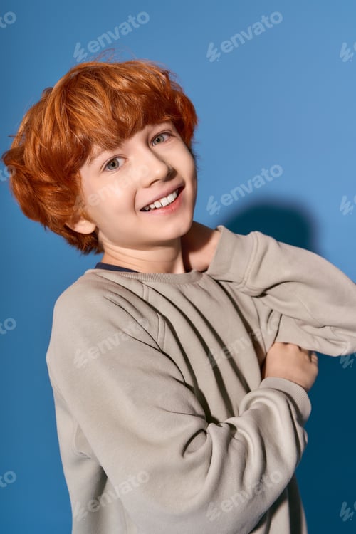 Preview: Stylish young boy showcasing his vibrant personality against a bold blue backdrop