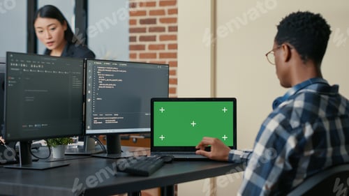 Preview: Database designer writing code using laptop with green screen chroma key mockup sitting at desk