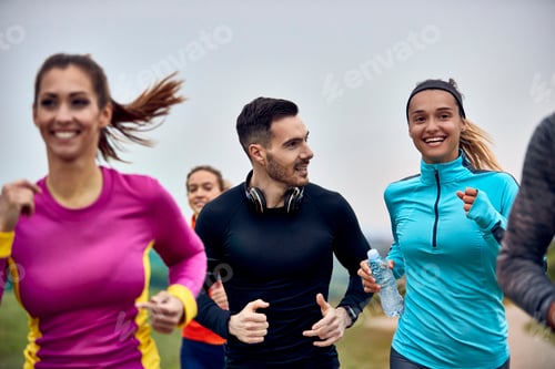 Preview: Happy athletic couple communicating while cross-country running.
