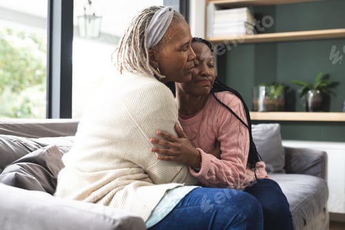 Preview: Happy african american senior mother and adult daughter sitting on couch and embracing