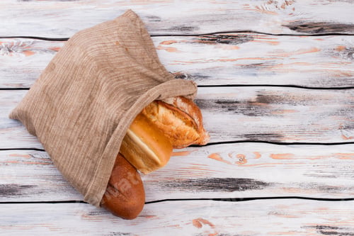 Preview: Bread in burlap sack on wooden background.