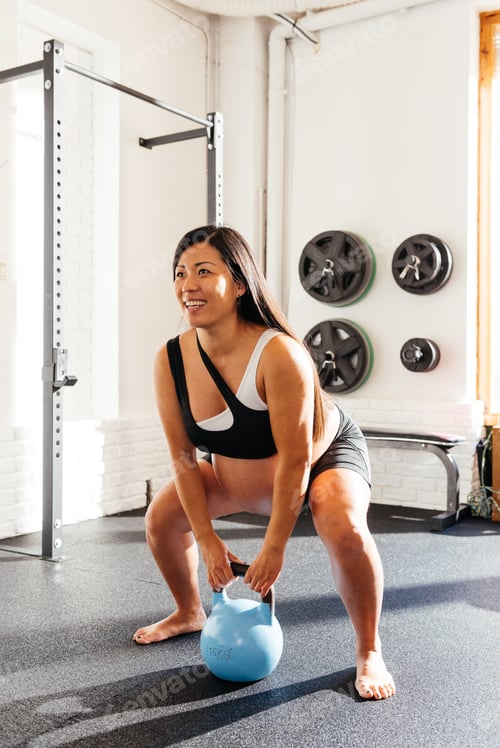 Preview: Smiling Pregnant Woman Exercising in a Gym, Lifting a Kettlebell During Her Fitness Routine