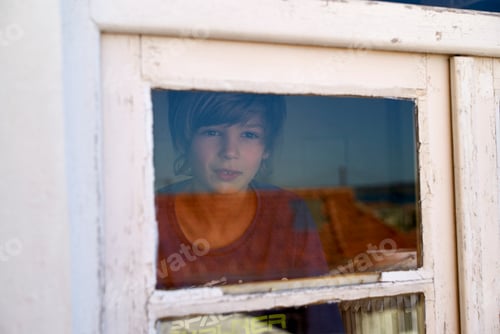 Preview: Young boy gazing through a vintage white window frame with a serene expression.