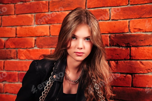 Preview: Girl With Long Hair Poses Against Red Brick Wall, Wearing Jacket and Chains