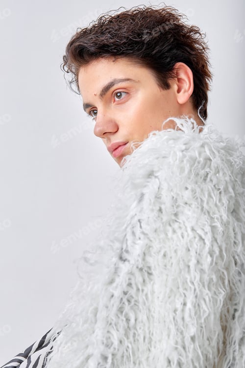 Preview: Profile portrait of young man in coat with natural make up posing as professional model