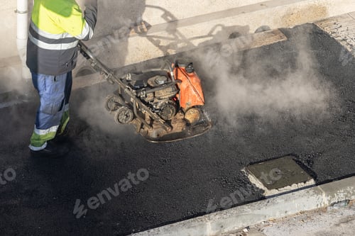Preview: Worker with a vibrating plate compactor machine working on a city street