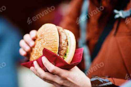 Burger Held in Red Napkin by Adult