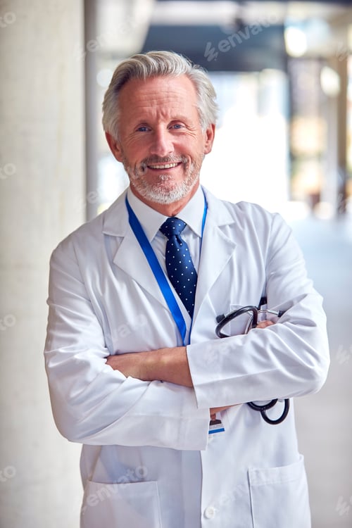 Preview: Portrait Of Smiling Mature Doctor Wearing White Coat Standing Inside Hospital Building