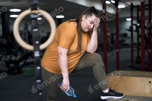 Preview: Overweight tired woman standing at the gym