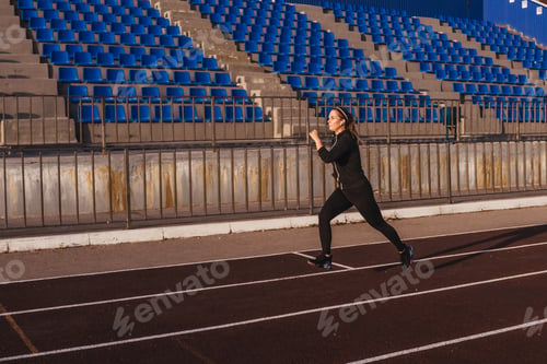 Preview: Young woman running at a track stadium