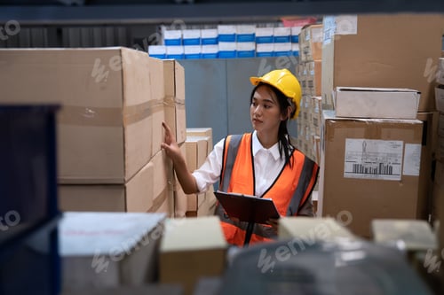 Preview: woman wearing visible vest hold clipboard in warehouse check and arrange box in the steel shelf