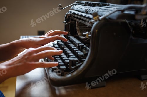 Preview: woman hands type on an old vintage dust-covered typewriter