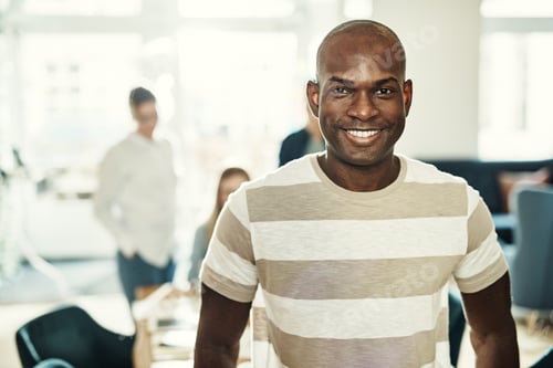 Preview: Young African designer smiling confidently with coworkers in the background