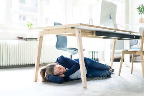 Vorschau: Geschäftsfrau liegt im Büro schlafend unter dem Tisch