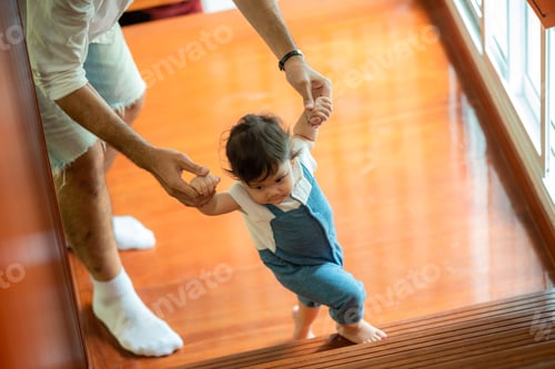Preview: cute toddler little child family concept, baby learning to walk with father and mother to help care