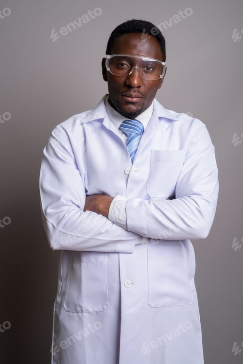 Preview: Young handsome African man doctor wearing protective glasses aga