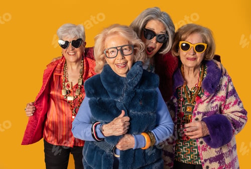 Preview: Four stylish senior women posing together on yellow background
