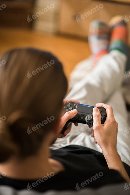 Preview: Rear view of man playing video game at home