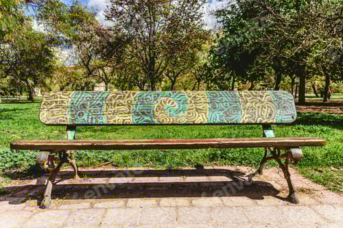 Preview: Wooden bench to rest decorated with a beautiful design of labyrinthine lines in a public garden.