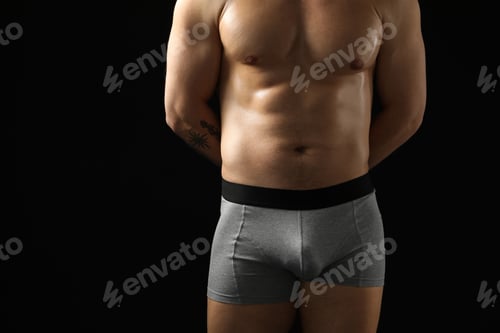 Preview: Young man in stylish light grey underwear on black background, closeup