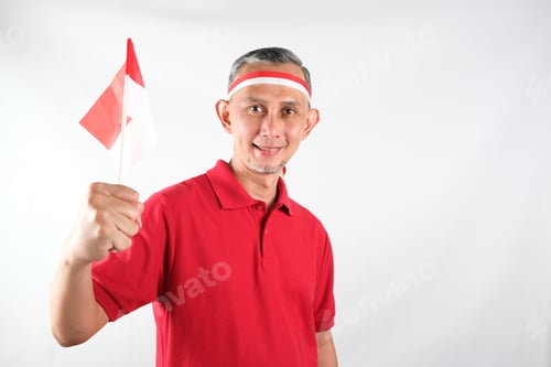 Preview: Portrait of Asian Man holding red and white Indonesia flag attribute.