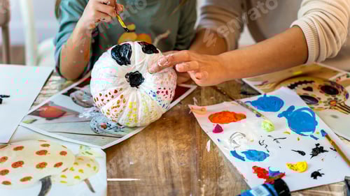 Preview: Children's drawing class. Little girl painting a pumpkin with her mom