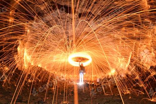 Preview: Long exposure shot of a person rotating a burning steel wool in a cave