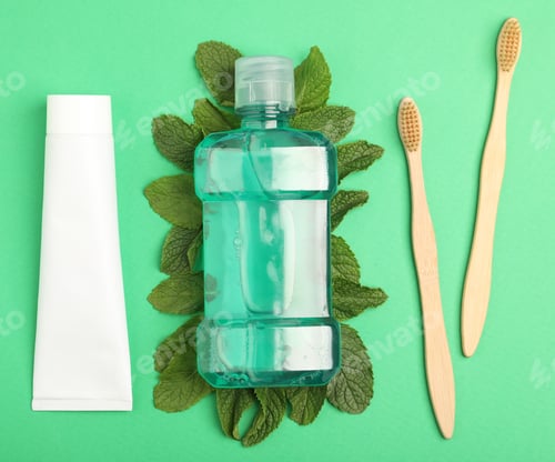 Preview: Mouthwash, other oral hygiene products and mint on green background, flat lay
