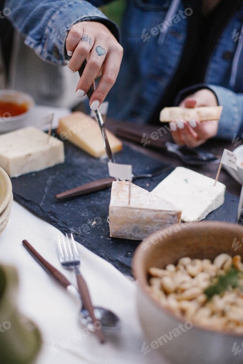 Preview: A woman using a knife to cut cheese on a slate board.