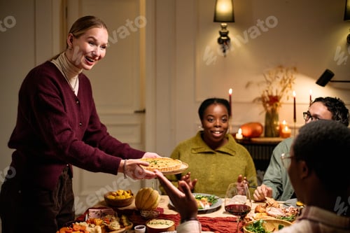 Preview: Young Caucasian Woman Serving Food to Diverse Friends during Thanksgiving Dinner