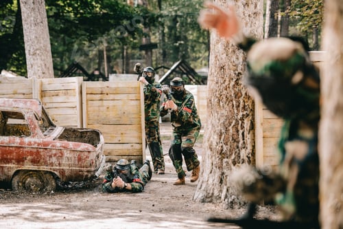 Preview: selective focus of paintball player doing follow me gesture to his paintball team in camouflage and