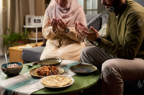 Preview: Young Muslim Man and Woman Praying before Eating Traditional Meal Indoors