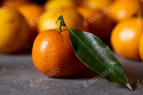 Preview: selective focus of sweet orange clementine with green leaf near tangerines