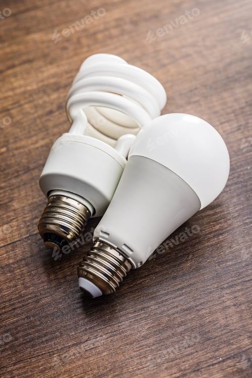 Preview: Energy saving light bulb . Fluorescent and led Lightbulb on wooden table.