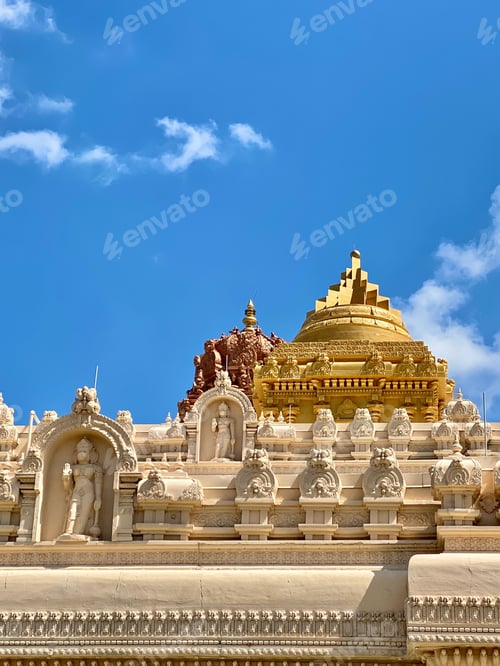Preview: Detailed view of the intricate carvings and golden dome of a Hindu temple against a clear blue sky