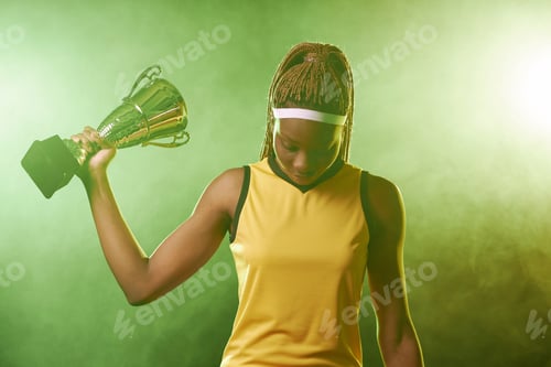 Preview: Black Female Athlete Holding Trophy Cup with Green Smoke in Background