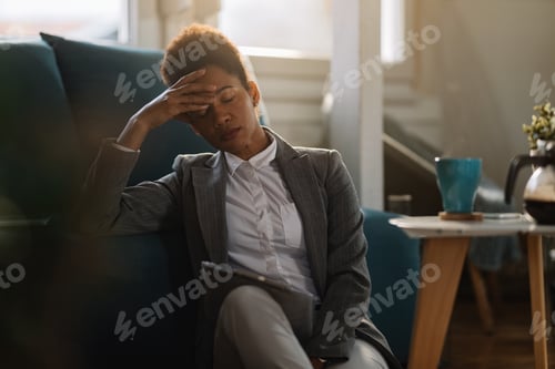 Preview: African American businesswoman feeling exhausted while working on reports at home.
