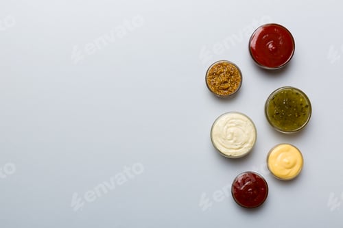 Preview: Different types of sauces in bowls on a colored Board . Top view. various sauces copy space